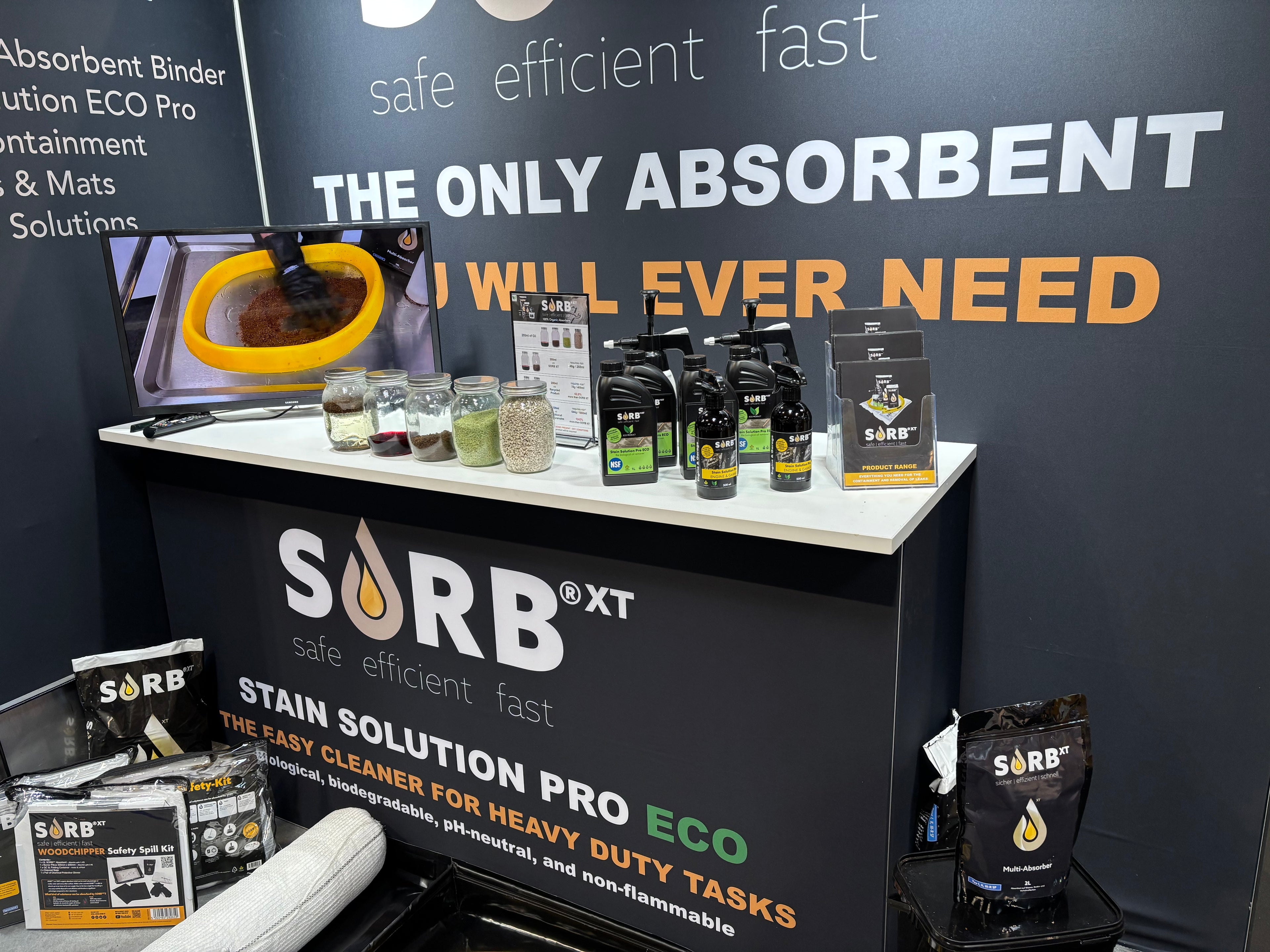 SORB XT stain solution display with products and branding on a dark wall.