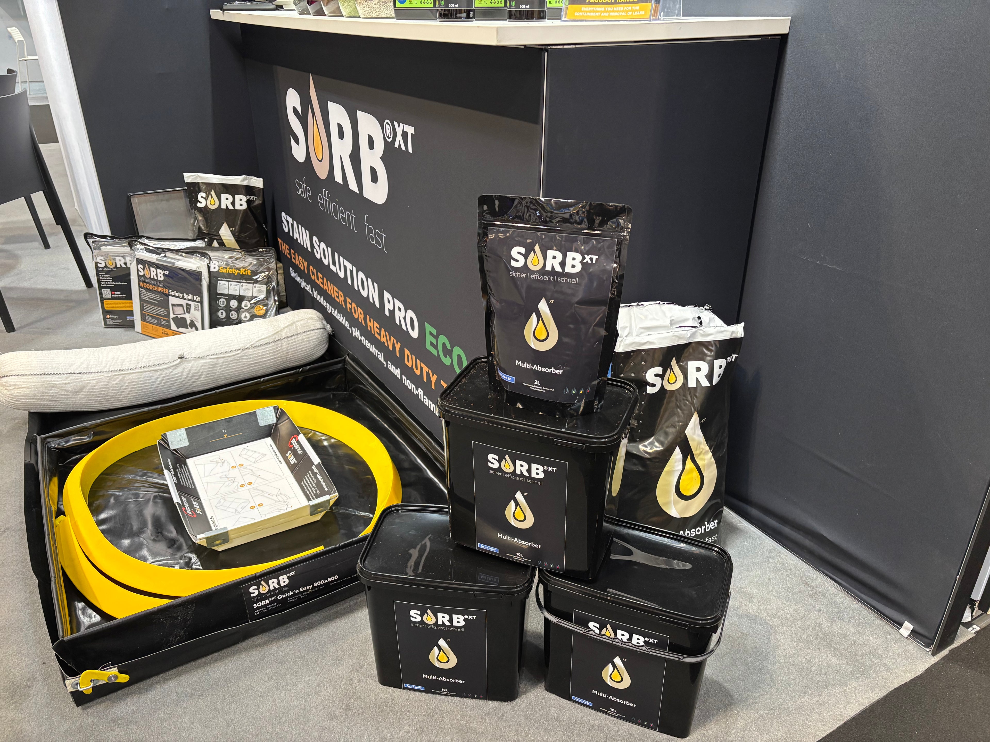 Display of SORB XT products including bags, boxes, and containers on a gray floor.