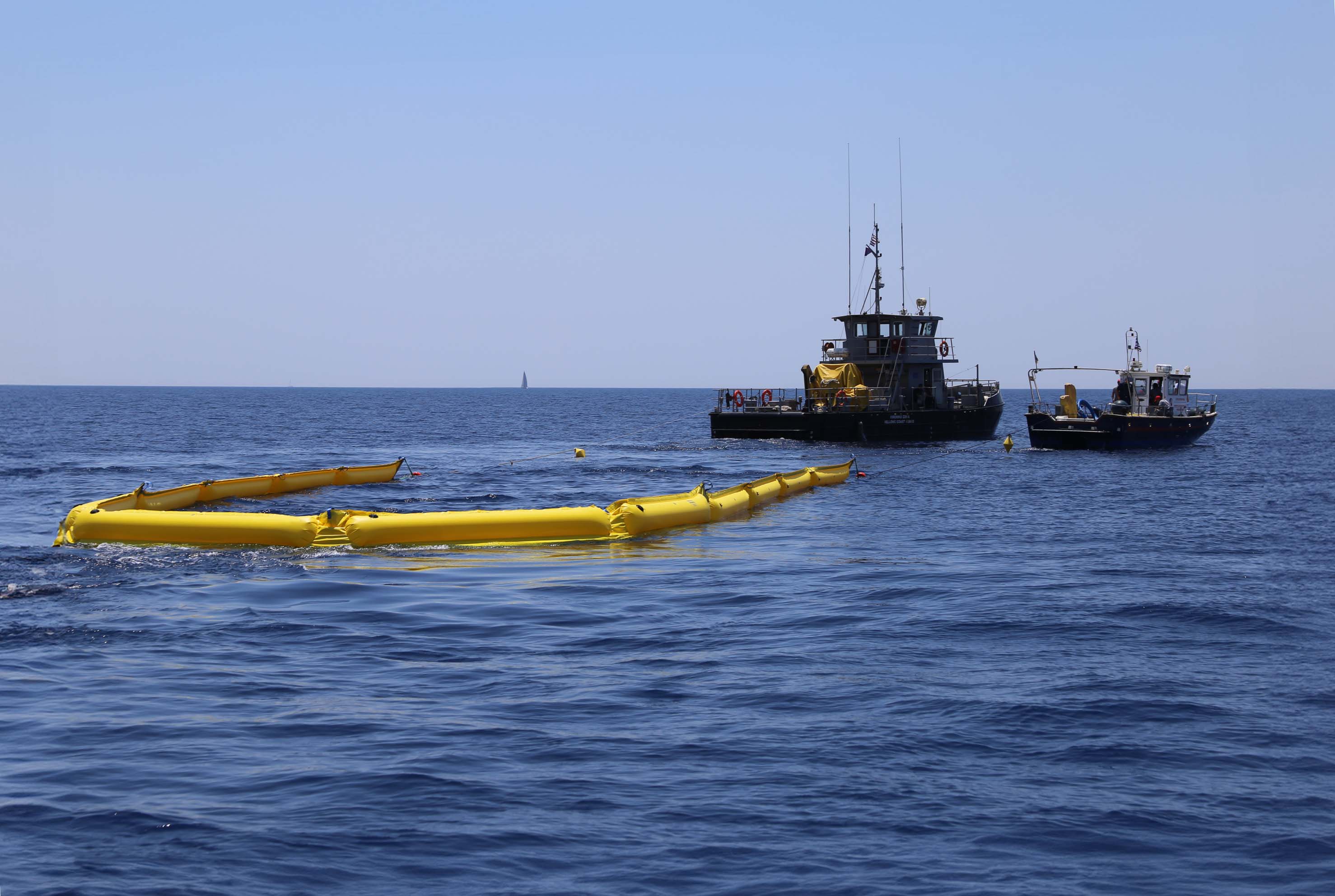 Two boats near a large yellow floating device on the ocean.